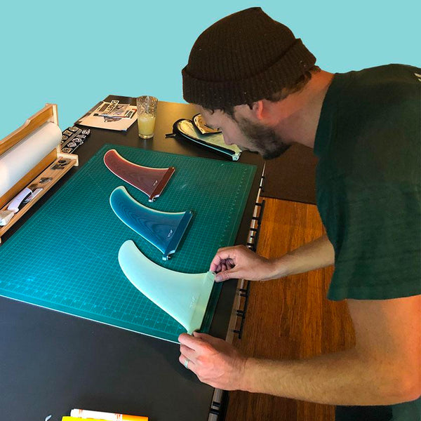 Tyler Warren for Captain Fin Co at a bench measuring up his new surfboard fins.